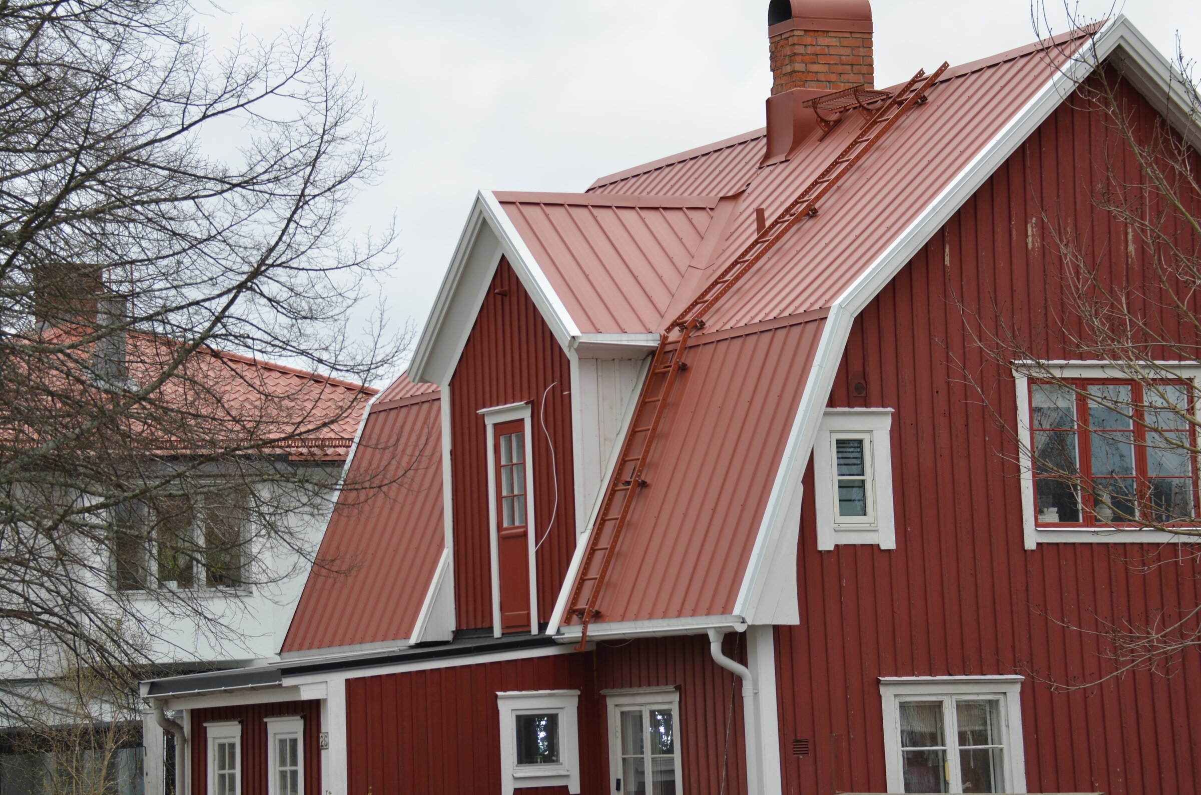 Rött hus med nytt pannplåtstak i tegelröd kulör, monterat av Arbetslag Bygg