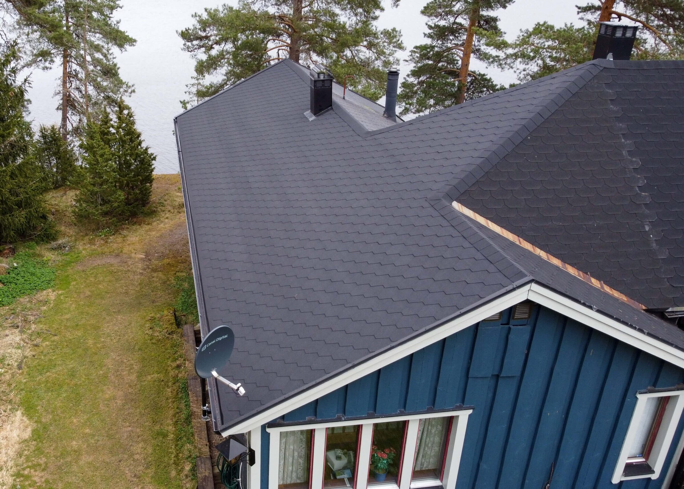 Drönarvy över ett nytt shingeltak i bitumen på en villa, lagt av Arbetslag Bygg