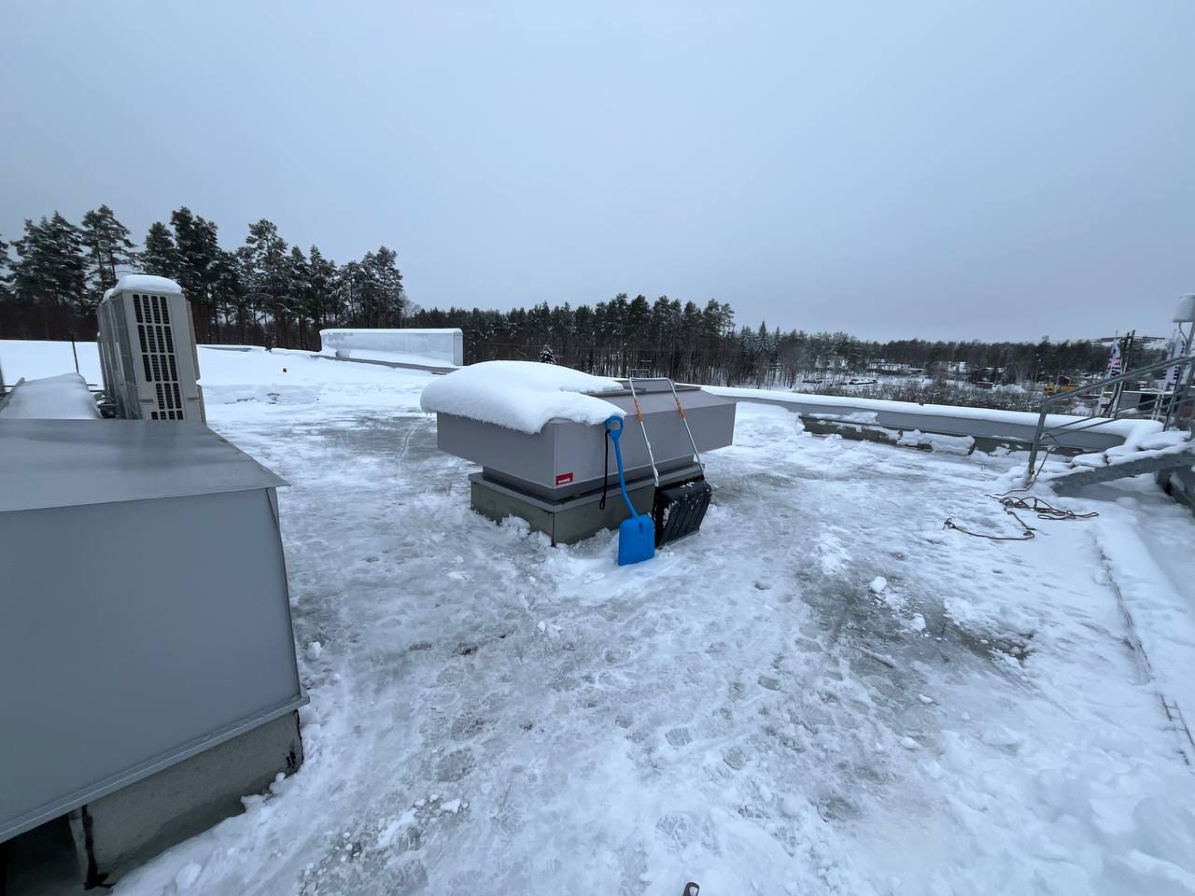 Snöröjning på ett platt industritak med snöskyffel, utförd av Arbetslag